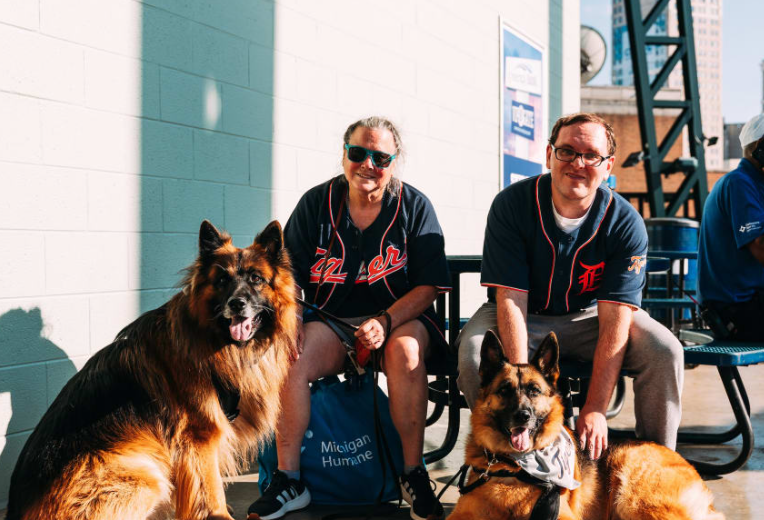 Two dogs and their owners at the Detroit Tiger stadium for Bark in the Park